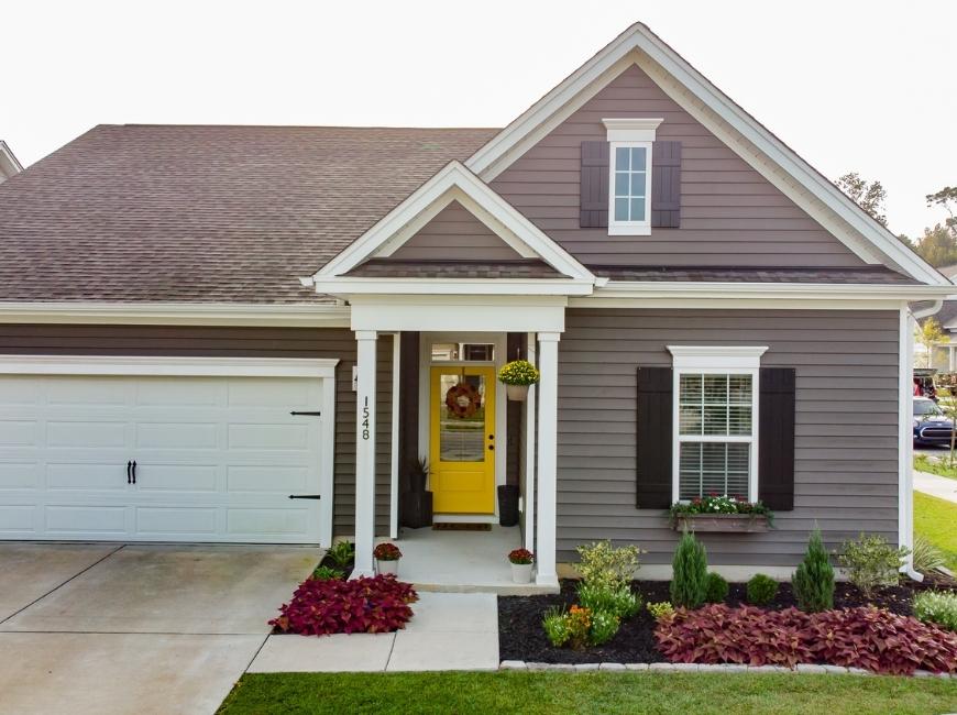 gray house with yellow door black shutters