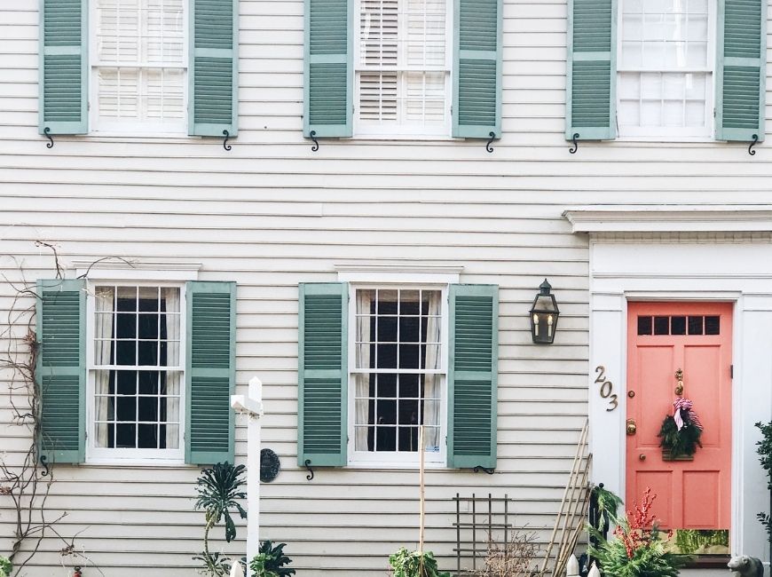 grey house with teal shutters and a peach door