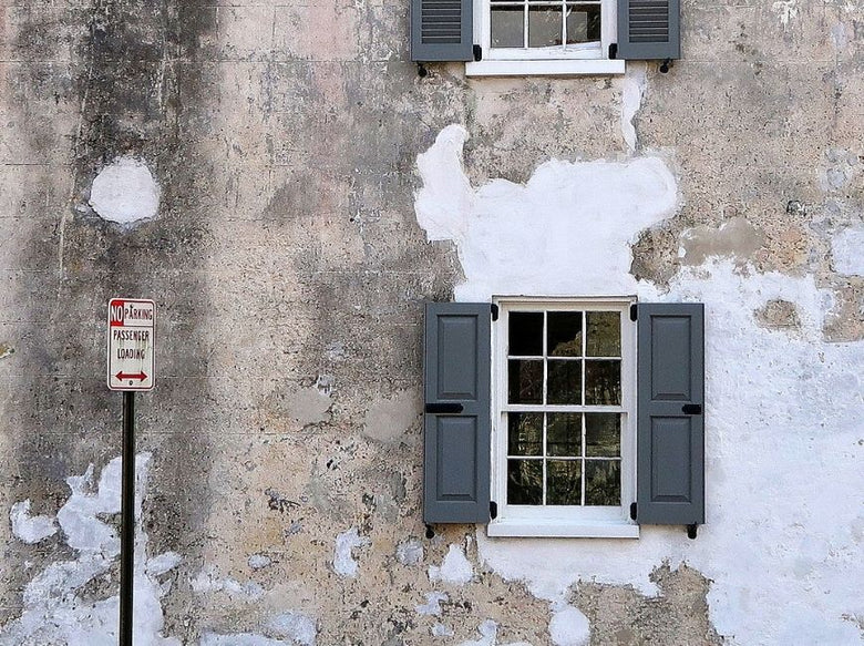 old grey building with grey/green shutters