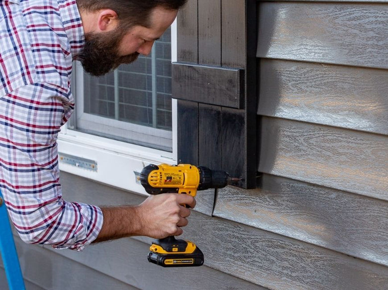 man installing shutters on home