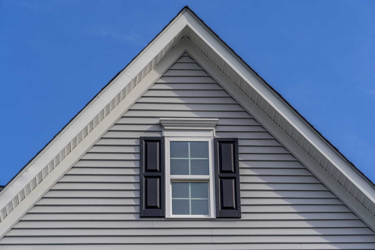 apex of a house roof with a window with black shutters